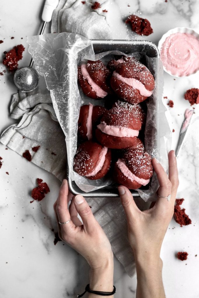 Taking a Red Velvet Whoopie Pie from a group in a baking dish.