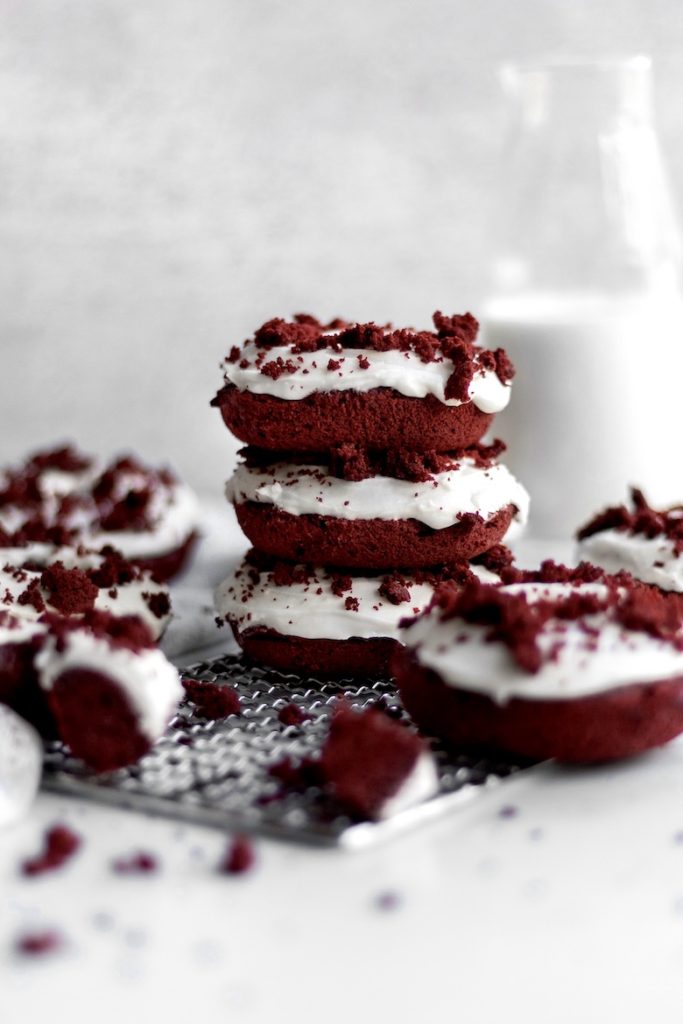 A stack of Red Velvet Donuts sits in front of a glass bottle of milk.