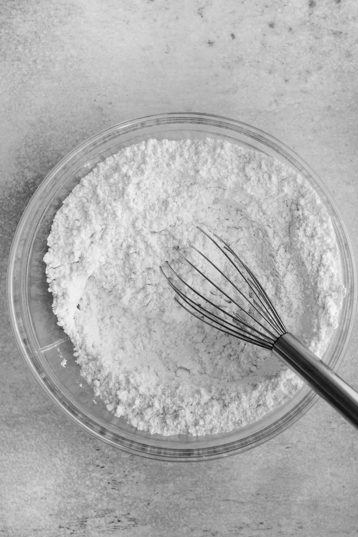A glass bowl whisking the dry ingredients.