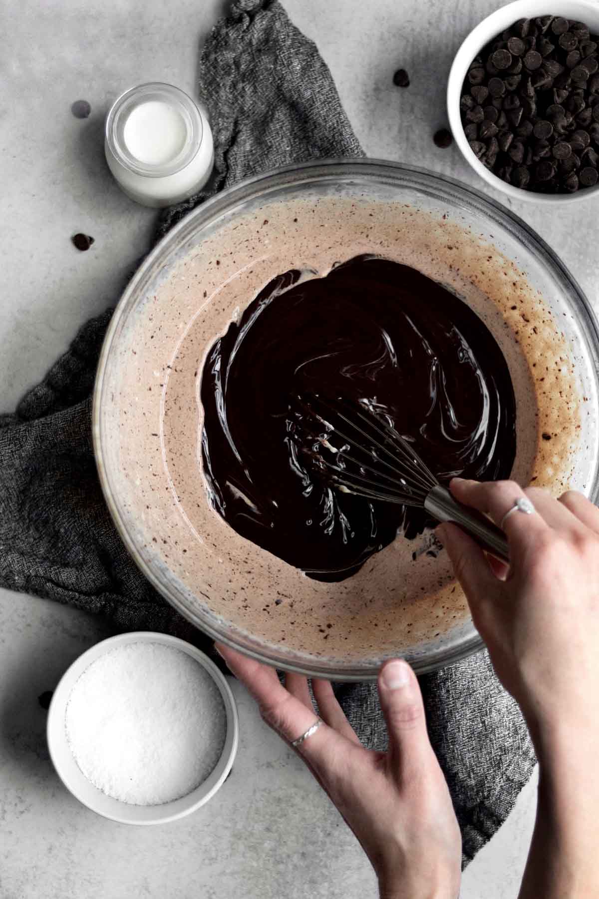Whisking the melted chocolate and heavy cream in a glass bowl.