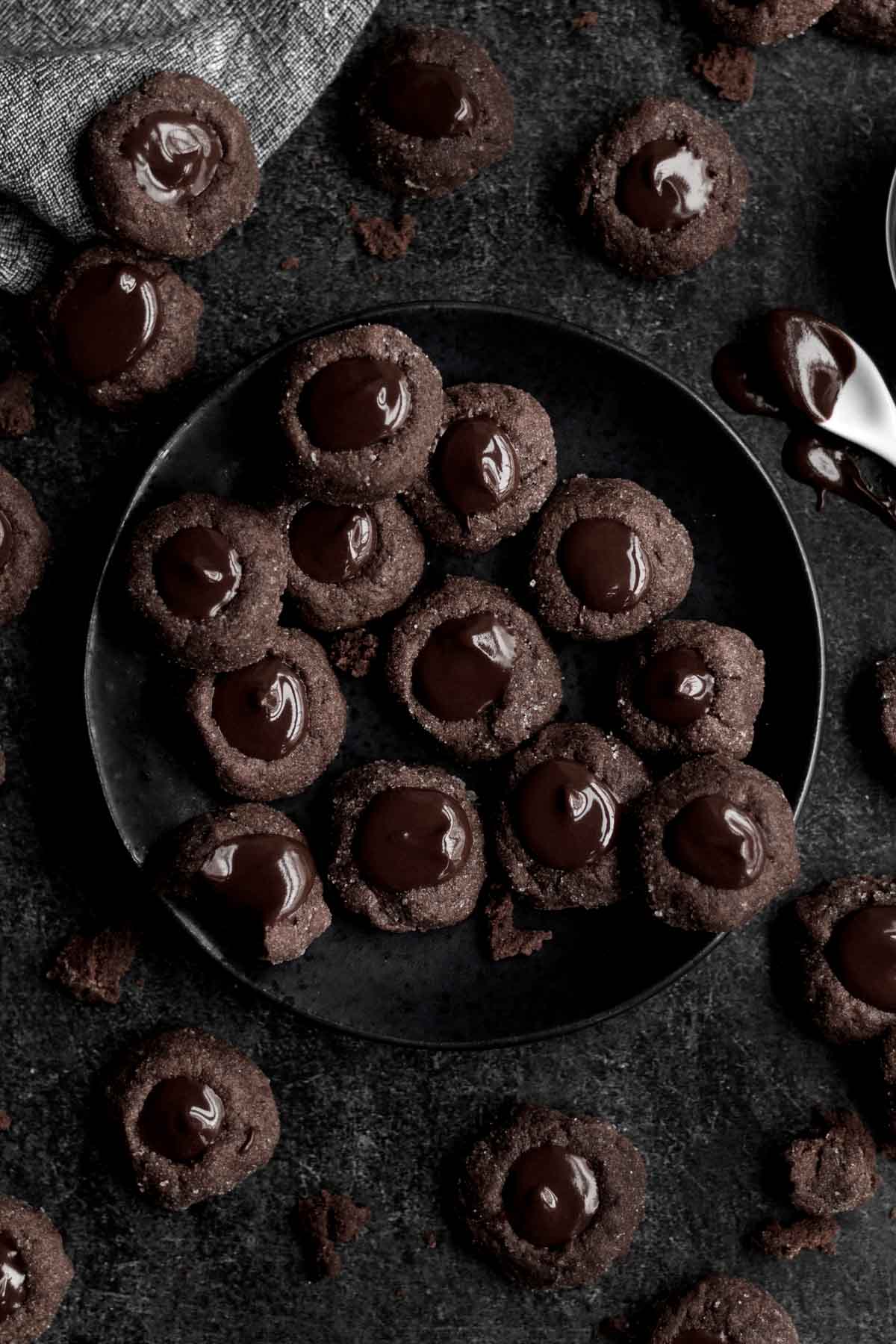 Chocolate Thumbprint Cookies arranged on a plate with chocolate ganache.