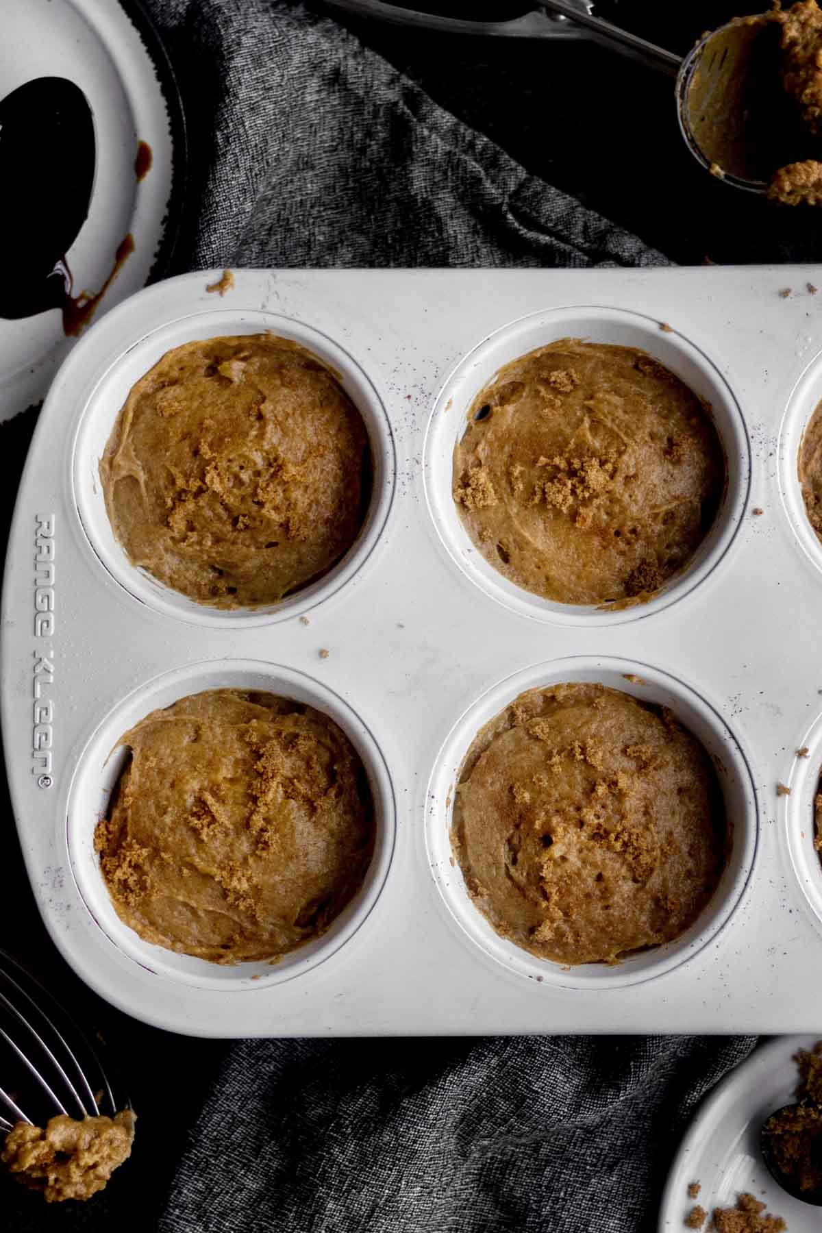 Filling the muffin tins to the very top with sprinkled brown sugar.