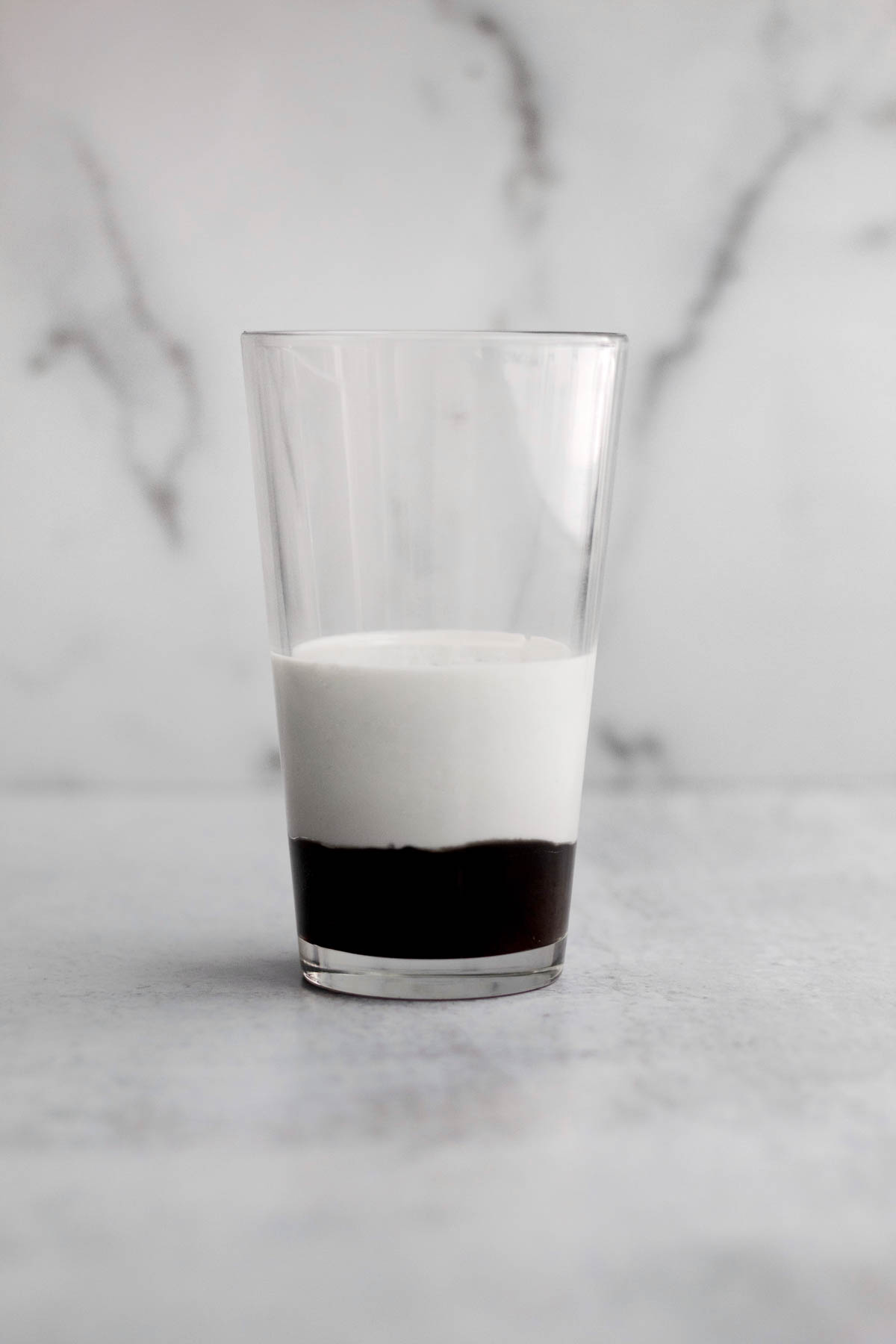 A glass with unmixed chocolate syrup and milk.