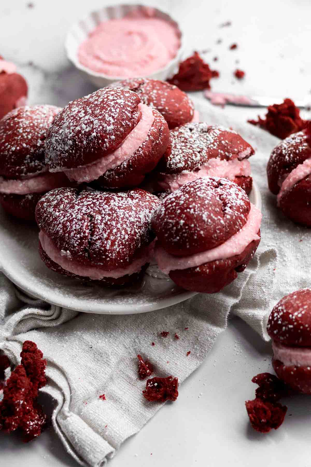 Red Velvet Whoopie Pies on a plate dusted with confectioners’ sugar.