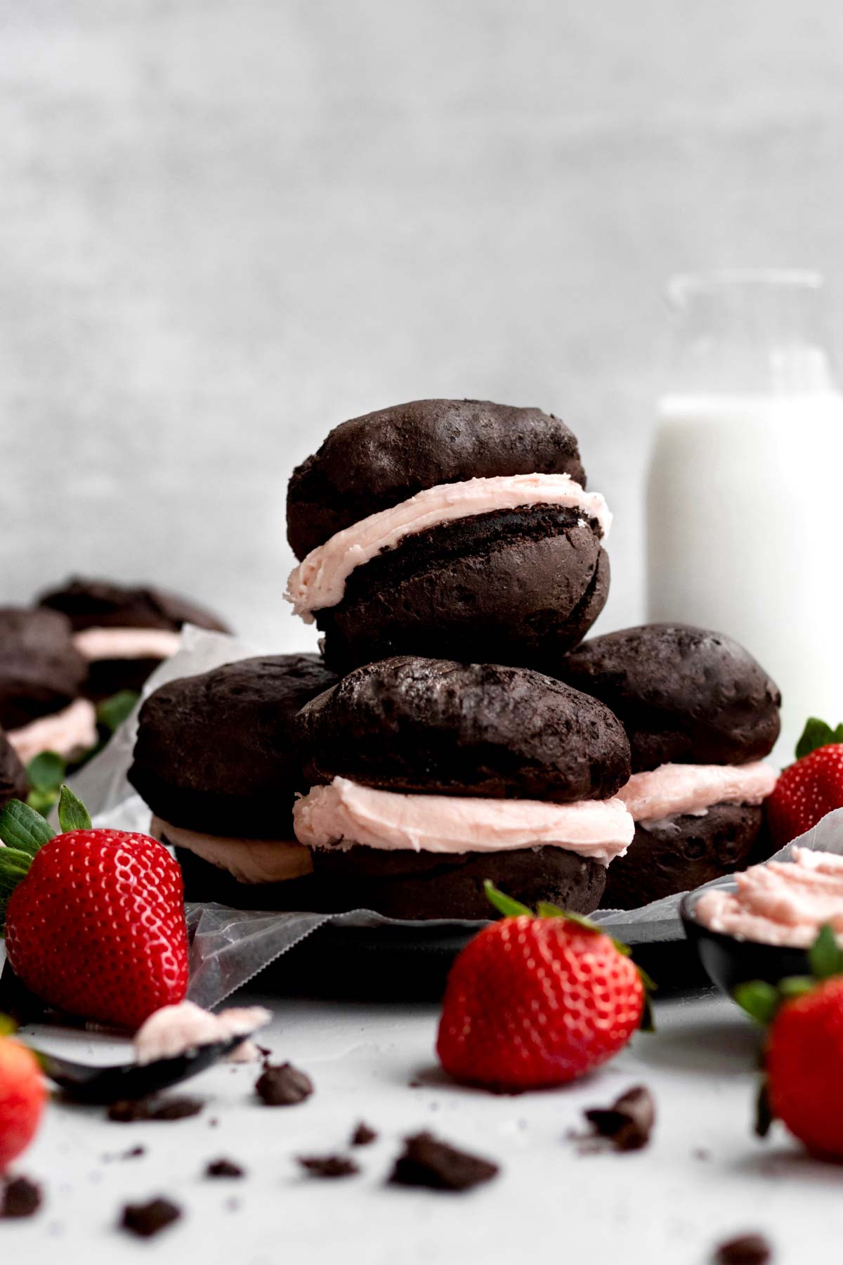 Four gluten free whoopee pies sit in a stack with strawberries.