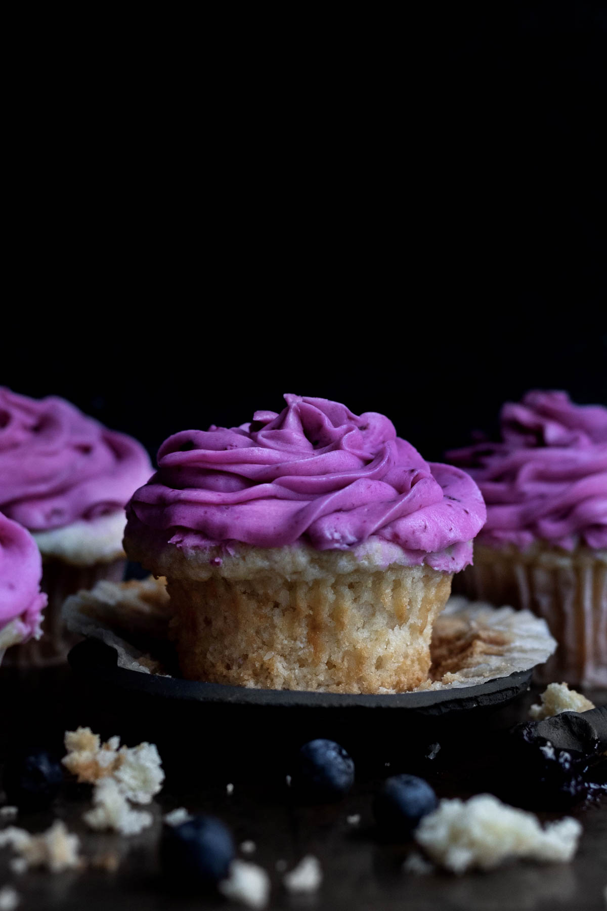 Gluten free Blueberry Cupcake sitting with a swirl of bright purple frosting.