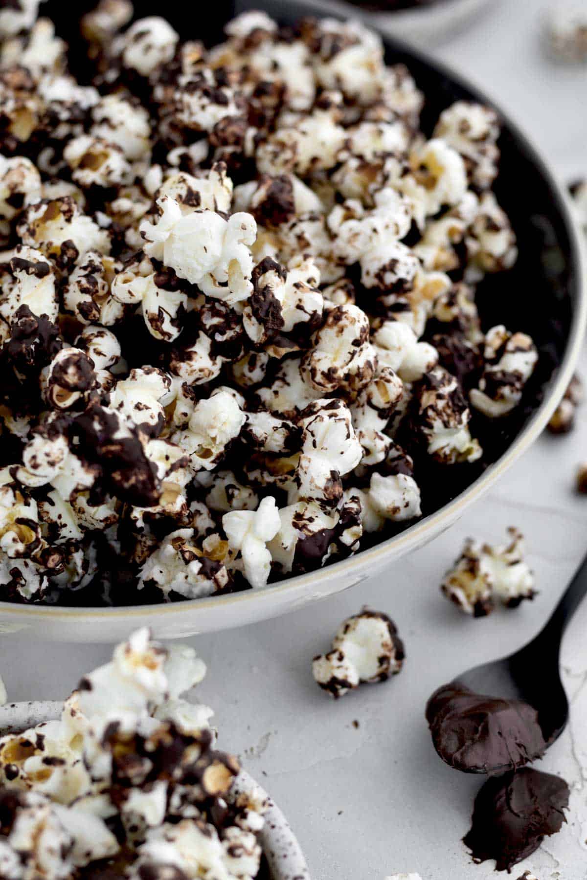 A hand picks a Chocolate Popcorn from a bowl.