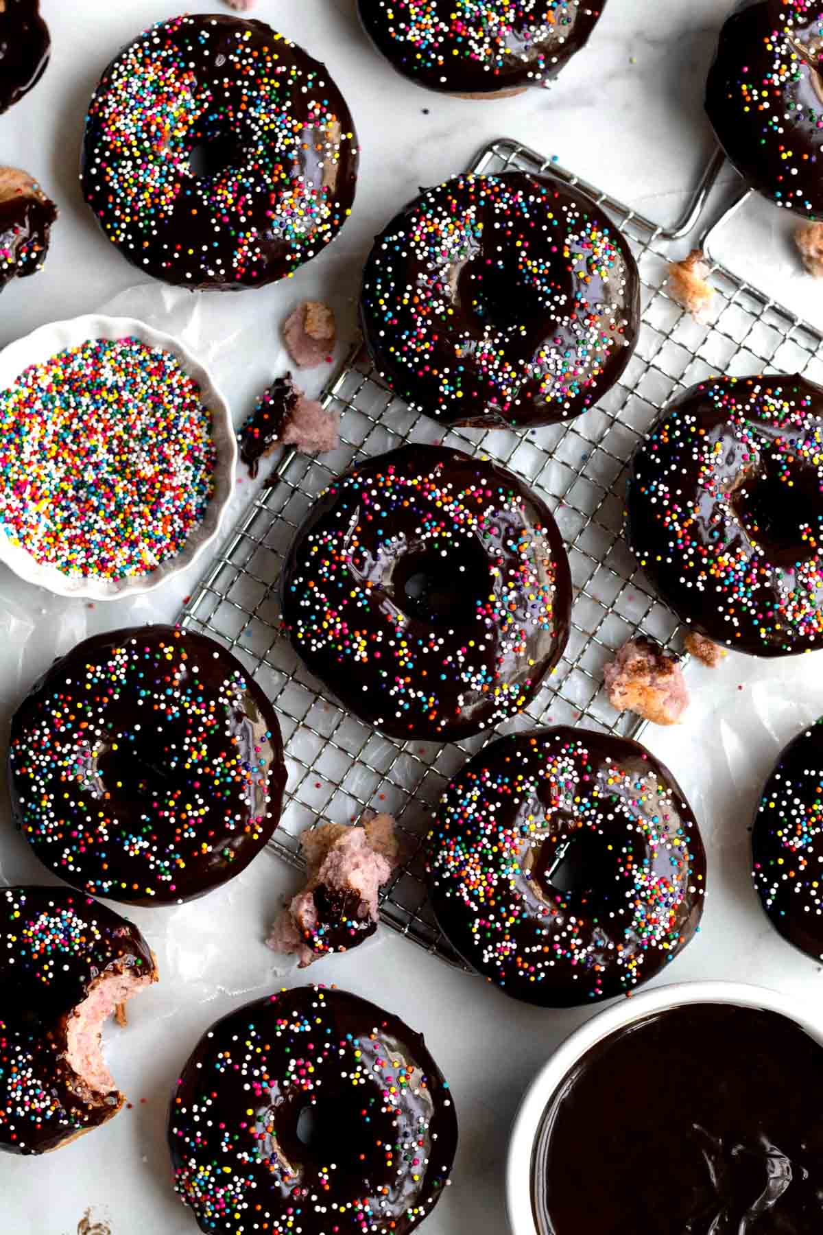 Gluten free Rainbow Donuts with chocolate frosting and rainbow colored sprinkles.