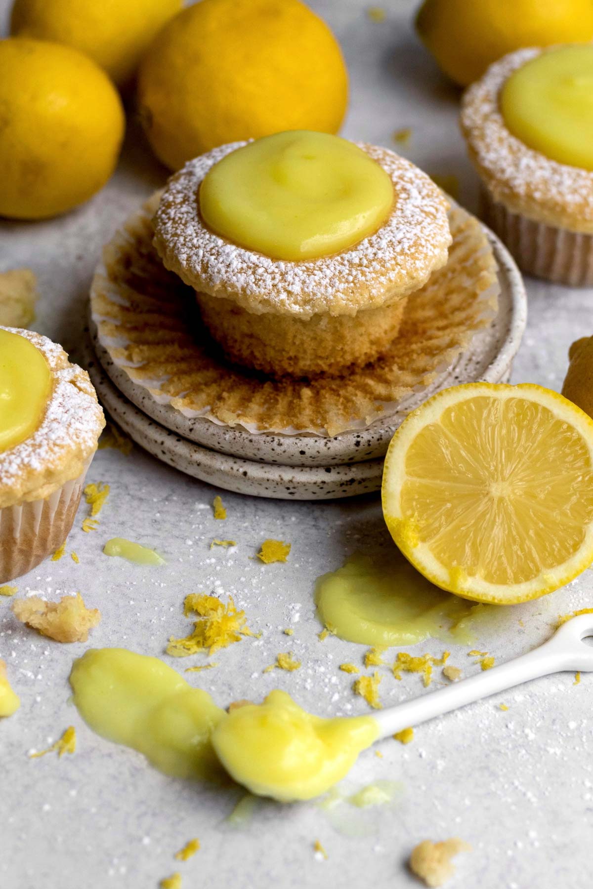 A stout Vegan Lemon Cupcake with lemon curd topping and confectioners’ sugar.