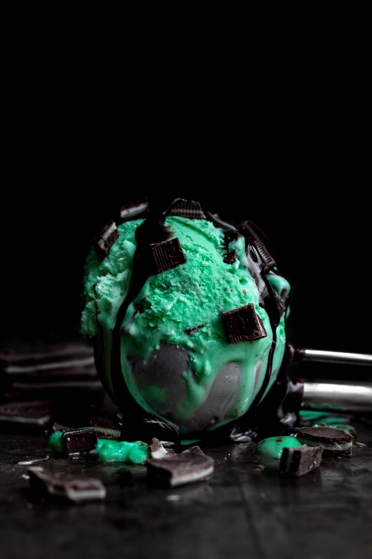Bright green Mint Ice Cream in a scoop with dark mint chunks.