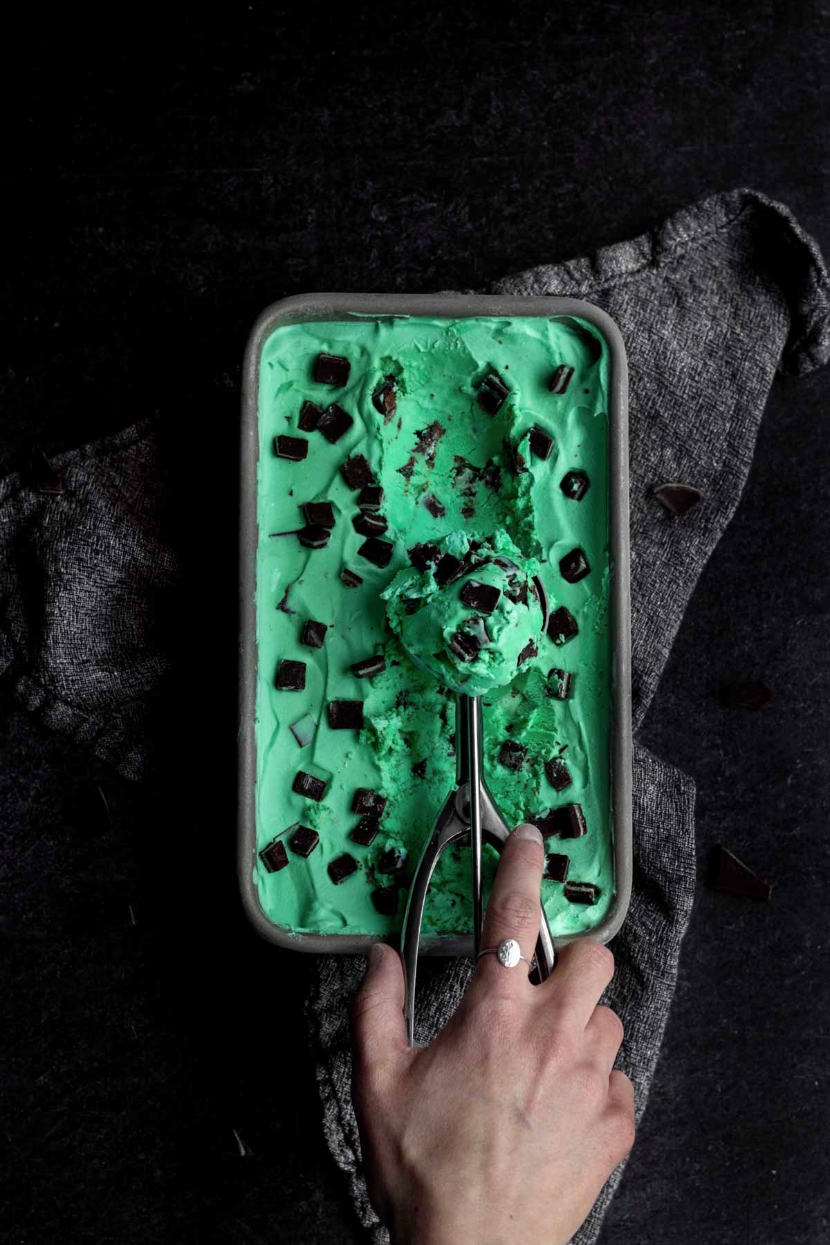 Scooping out frozen Mint Ice Cream from a loaf pan.